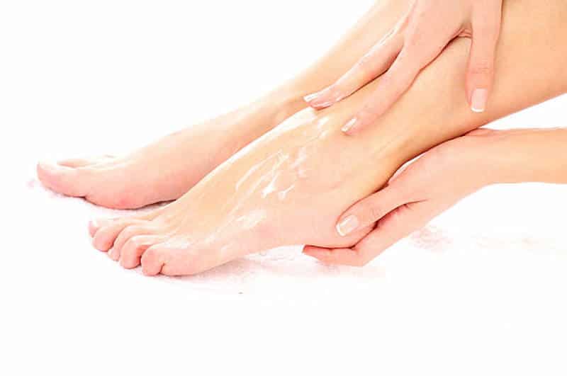 A woman moisturizing her feet 